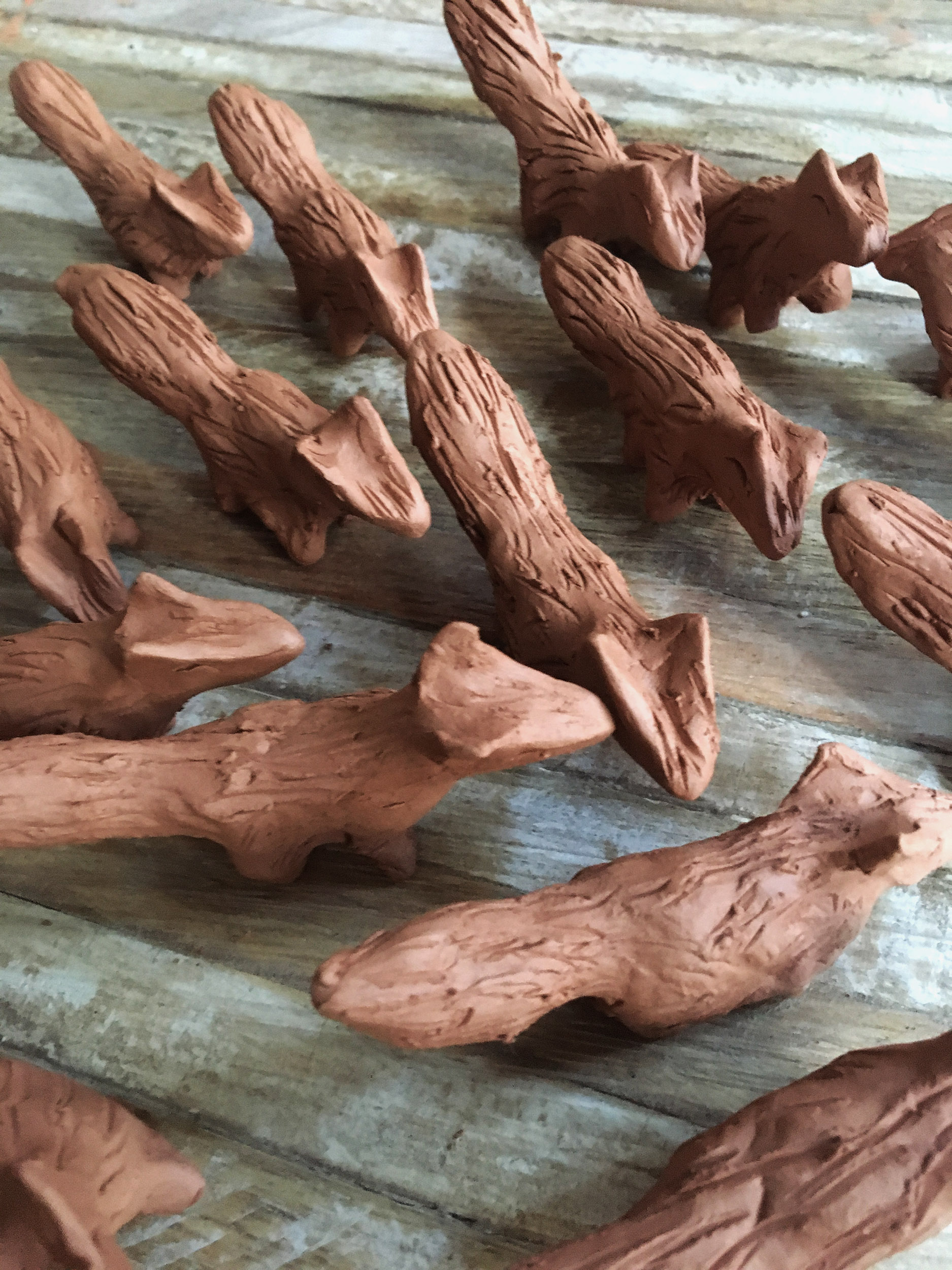 Des dizaines de petites sculptures de renard en terre crue rouge.